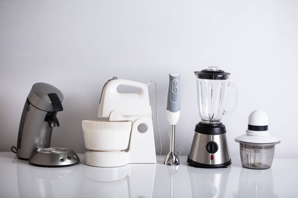 Variety Of Kitchen Appliances In Row Over Reflective Desk - Foto, immagini