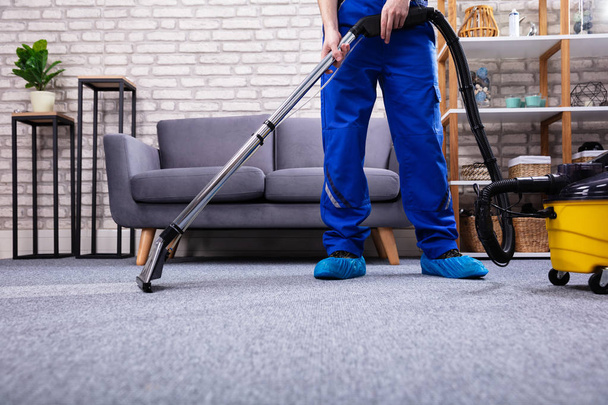 Human Cleaning Carpet In The Living Room Using Vacuum Cleaner At Home - Foto, afbeelding