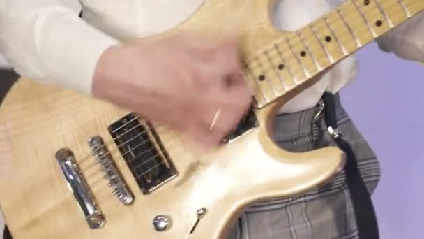 Ροκ μουσικός παίζει κίτρινη ηλεκτρική κιθάρα, στη σκηνή με έγχρωμο φως - Πλάνα, βίντεο