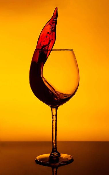 A wine glass with a splash of wine on a yellow background.  A glass on the bar in a cafe, restaurant, nightclub or disco. - Valokuva, kuva