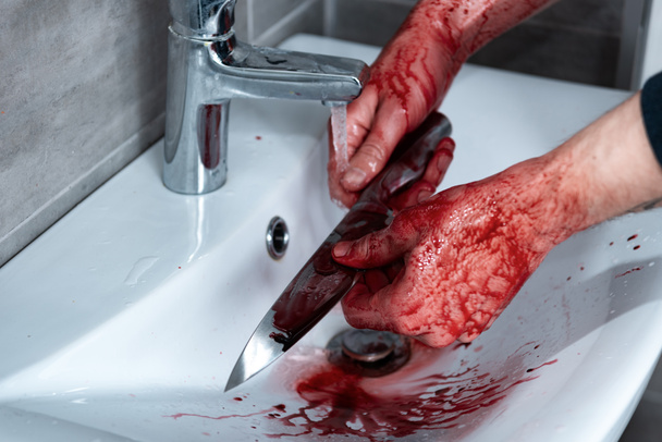 cropped view of killer washing knife in sink after murder - Foto, Bild