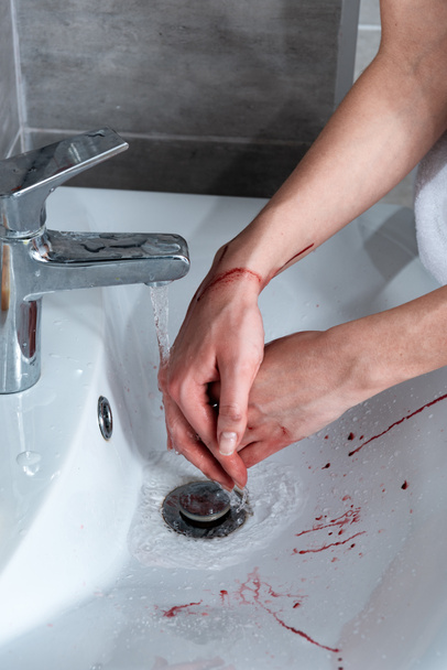 vista parcial de la mujer lavándose las manos sangrantes en el baño
 - Foto, Imagen