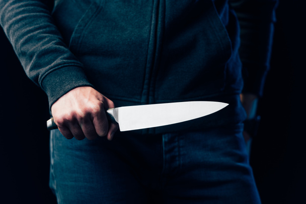обрезанный вид убийцы, держащего нож изолированный на черном
 - Фото, изображение