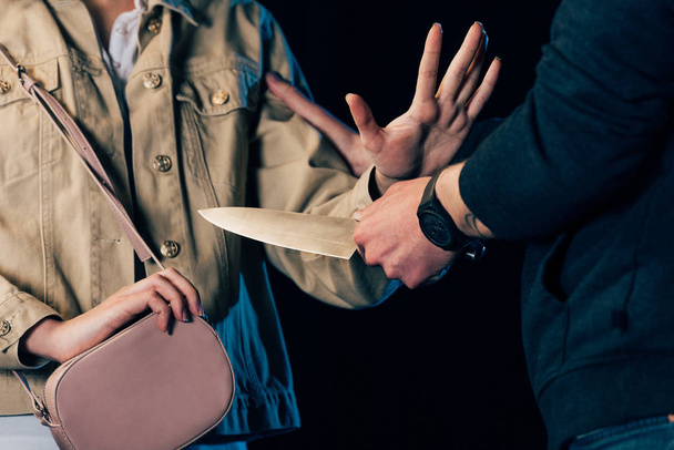 vista parcial de mujer atacante criminal con cuchillo aislado en negro
 - Foto, imagen