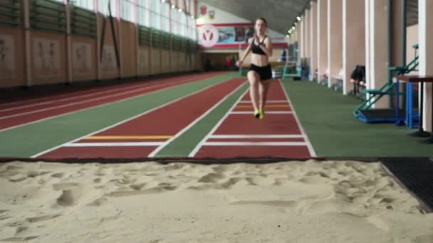 Lány sportoló teljesítő hosszú ugorj be homokozóban - Felvétel, videó
