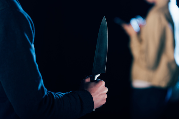cropped view of killer holding knife near woman isolated on black - Photo, Image