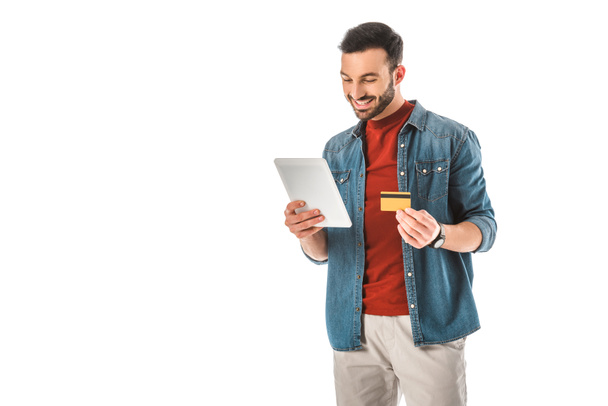 白で隔離されたデジタルタブレットを使用しながら、クレジットカードを持っている笑顔の男 - 写真・画像