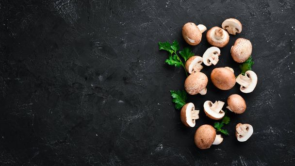 Mushrooms on a black stone background. Champignons Top view. Free copy space. - Foto, Bild