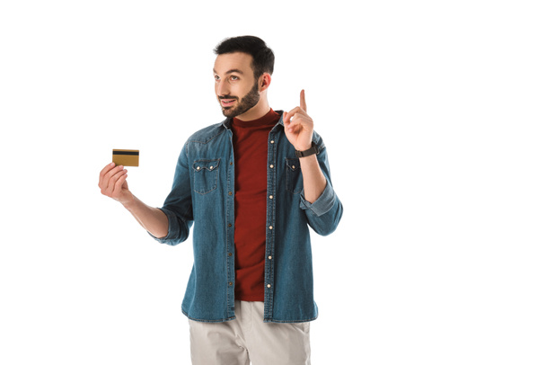 sonriente hombre sosteniendo idea signo mientras sostiene tarjeta de crédito aislado en blanco
 - Foto, Imagen