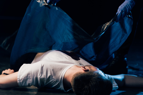 częściowy widok badacza obejmującego martwego człowieka na scenie zbrodni - Zdjęcie, obraz