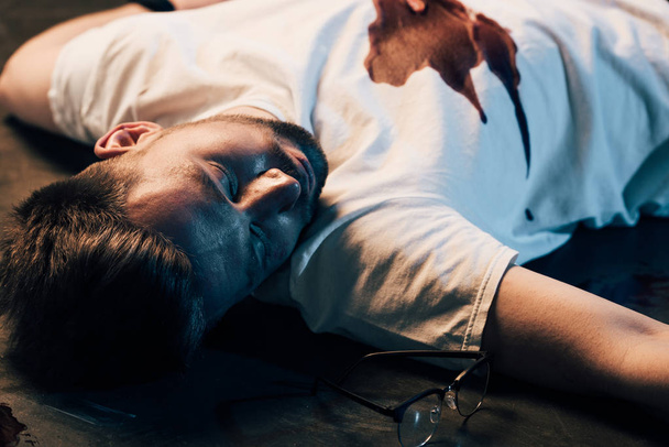 martwy człowiek z krwią na t-shirt na podłodze na scenie zbrodni - Zdjęcie, obraz