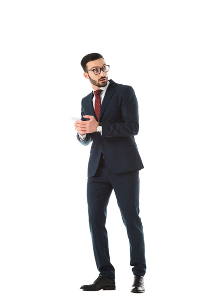 surprised businessman looking while using smartphone isolated on white - Zdjęcie, obraz