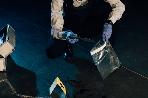 cropped view of investigator putting knife in ziploc bag at crime scene - Foto, Imagen