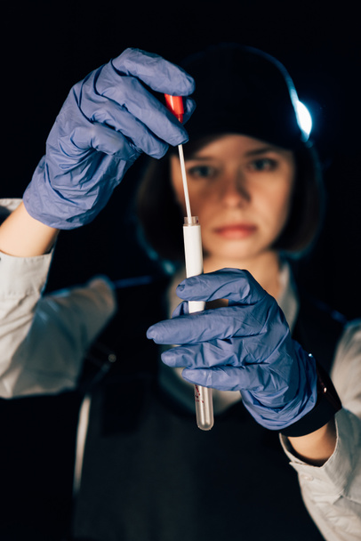 selective focus of investigator in rubber gloves holding swab and test tube at crime scene - Photo, Image
