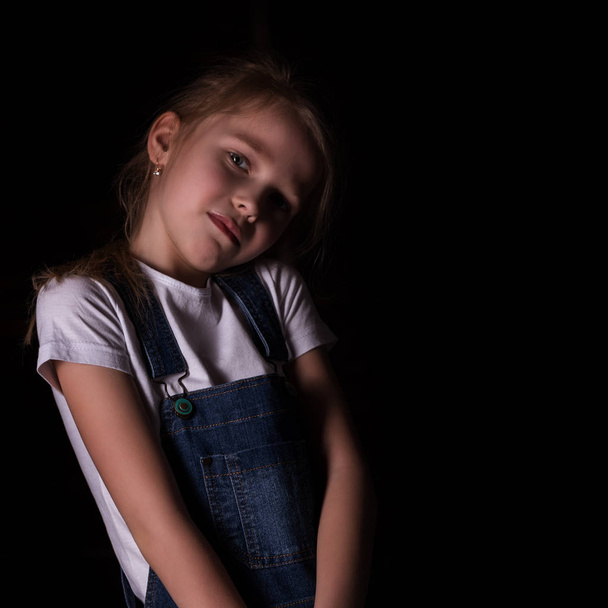 beautiful blonde little girl on a dark background. She stands in different poses and shows different emotions. free space for your text - Фото, изображение
