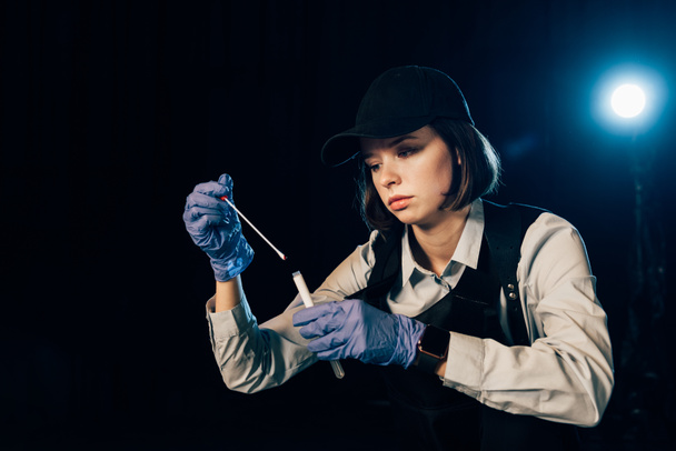 investigador en guantes de goma sosteniendo hisopo y tubo de ensayo en la escena del crimen
 - Foto, Imagen
