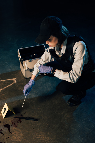 investigaror in gloves holding test tube and swab at crime scene - Photo, Image