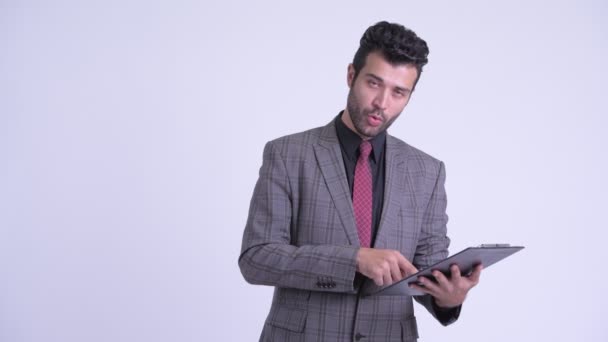 Bearded Persian businessman talking while reading on clipboard - Záběry, video