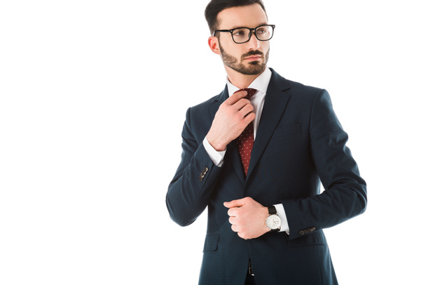 serious businessman touching tie and looking away isolated on white - Foto, Imagem