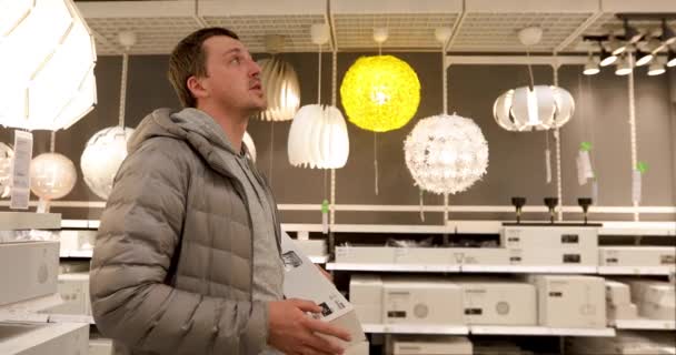 Único homem está segurando uma lâmpada na loja doméstica
 - Filmagem, Vídeo