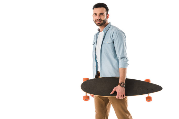 handsome smiling man holding longboard and looking at camera isolated on white - Photo, Image