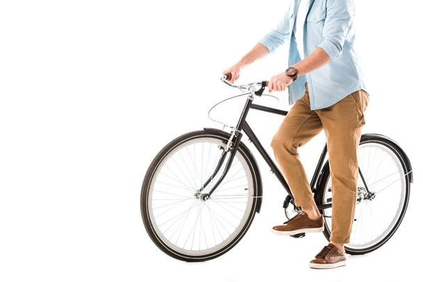 partial view of man in beige trousers near bicycle isolated on white - Foto, imagen