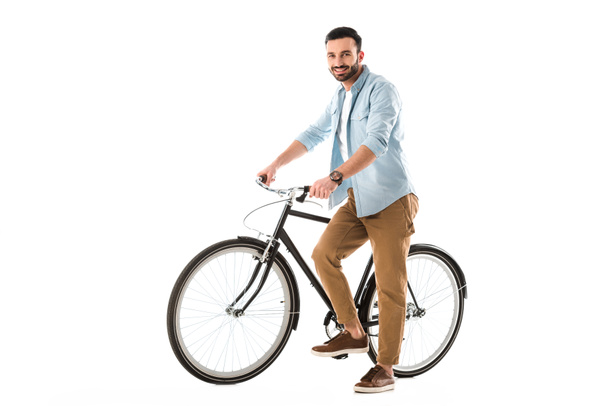guapo hombre alegre con la bicicleta sonriendo a la cámara aislado en blanco
 - Foto, Imagen