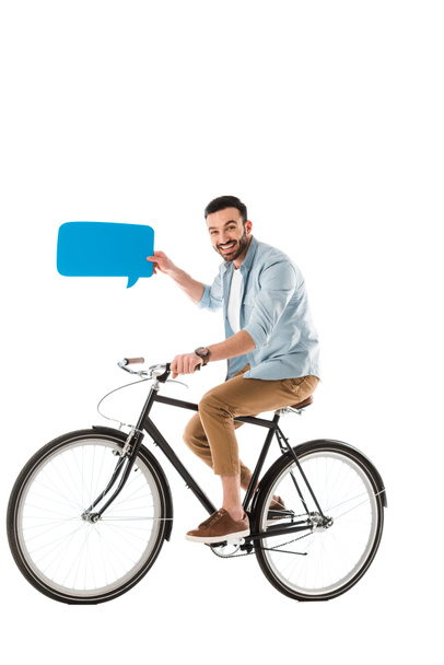 smiling handsome man holding speech bubble and riding bicycle isolated on white - 写真・画像