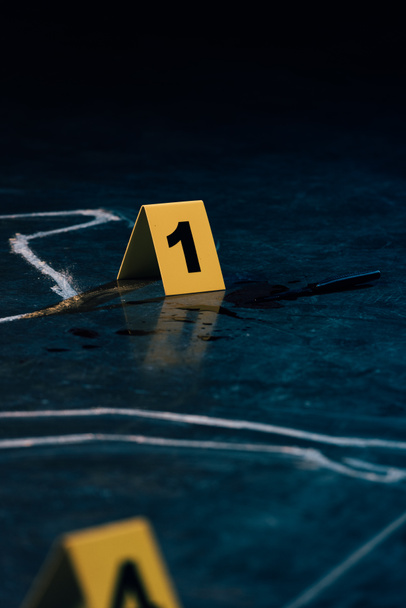 selective focus of chalk outline and evidence markers at crime scene - Photo, Image