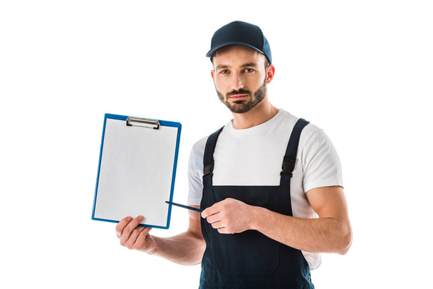 serious delivery man pointing with pen at clipboard with empty paper and looking at camera isolated on white - Foto, Imagem