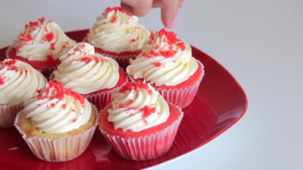 Woman preparing cupcake red velvet. Sprinkle cream with crumbs. The finished cakes are on the plate. - Materiaali, video
