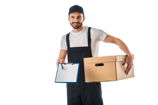handsome smiling delivery man with cardboard box holding clipboard with blank paper and looking at camera isolated on white - 写真・画像