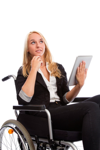 Blond girl sitting in a wheel chair with tablet PC - Valokuva, kuva