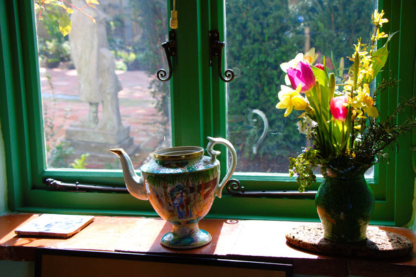 Díszített ablakpárkányon virágok egy váza és egy tea kancsó. - Fotó, kép