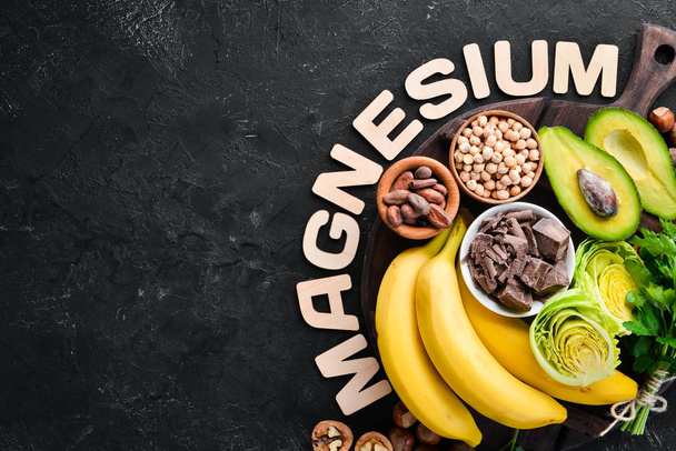 Foods containing natural magnesium. Mg: Chocolate, banana, cocoa, nuts, avocados, broccoli, almonds. Top view. On a black background. - Fotoğraf, Görsel