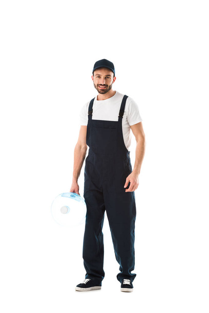 happy delivery man holding bottle of water and looking at camera isolated on white - Photo, Image