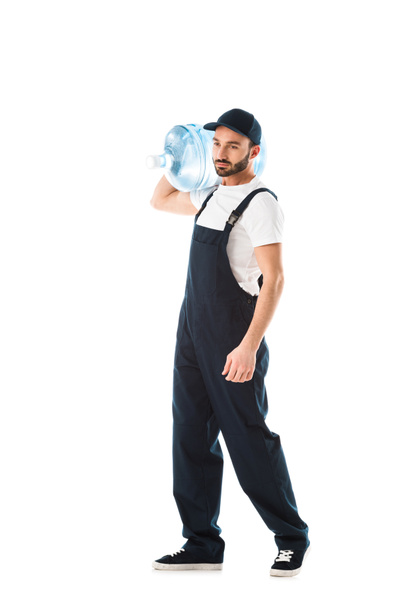 σοβαρός άνθρωπος παράδοσης σε φόρμες που μεταφέρουν μπουκάλι νερό που απομονώνεται σε λευκό - Φωτογραφία, εικόνα