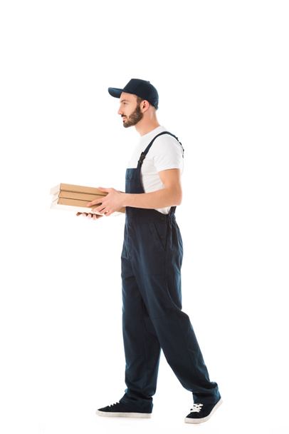 serious delivery man in overalls carrying pizza boxes isolated on white - Foto, imagen