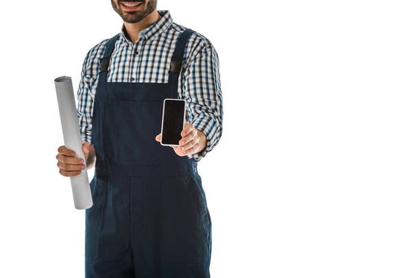 vista parcial del trabajador de la construcción sosteniendo teléfono inteligente con pantalla en blanco y papel laminado aislado en blanco
 - Foto, Imagen