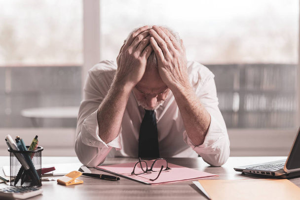 Стрессовый бизнесмен, сидящий в офисе
 - Фото, изображение