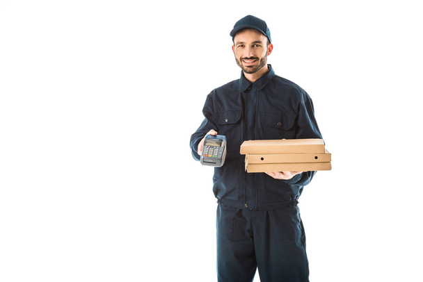 mensajero sonriente en overoles con terminal de pago y cajas de pizza aisladas en blanco
 - Foto, Imagen