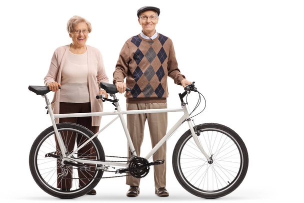 Full length portrait of a senior man and woman standing with a tandem bicycle isolated on white background - Fotografie, Obrázek