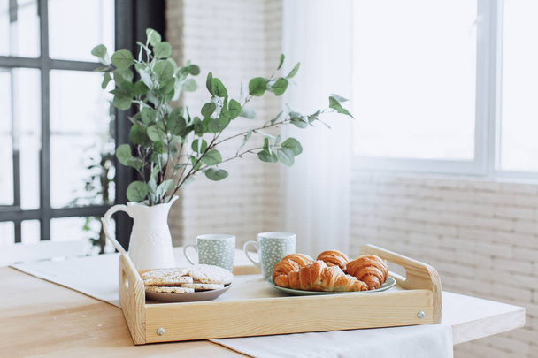 Placa con croissants de pie sobre mesa de madera en la cocina
. - Foto, Imagen