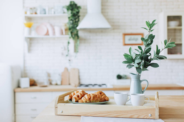 Plate with croissants standing on wooden table in the kitchen. - 写真・画像