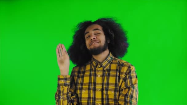 A fiatal afro-amerikai férfi csendet vagy bla bla gesztust mutat zöld vásznon vagy krómkulcsos háttérrel. Az érzelmek fogalma - Felvétel, videó
