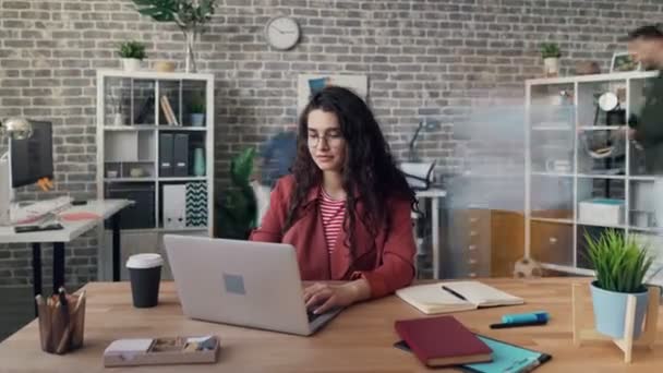 Nagyítás a fiatal nő, aki laptopot használ a projekt az irodában - Felvétel, videó