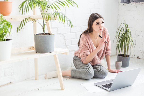 Young woman sits on the floor in a Scandinavian apartment interior with a laptop, studying law, freelance girl at work, distance learning student, online employment, paperwork and outsourcing concept - Fotó, kép