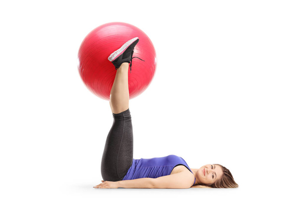 Full length shot of a young woman lying on the floor and holding a fitness ball with legs isolated on white background - Φωτογραφία, εικόνα