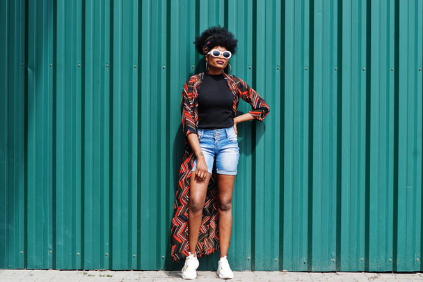 African woman with afro hair, in jeans shorts and white sunglass - Fotoğraf, Görsel