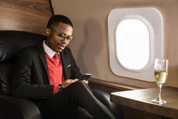 Successful young Afro American black businessman sitting in the chair of his private jet - Valokuva, kuva